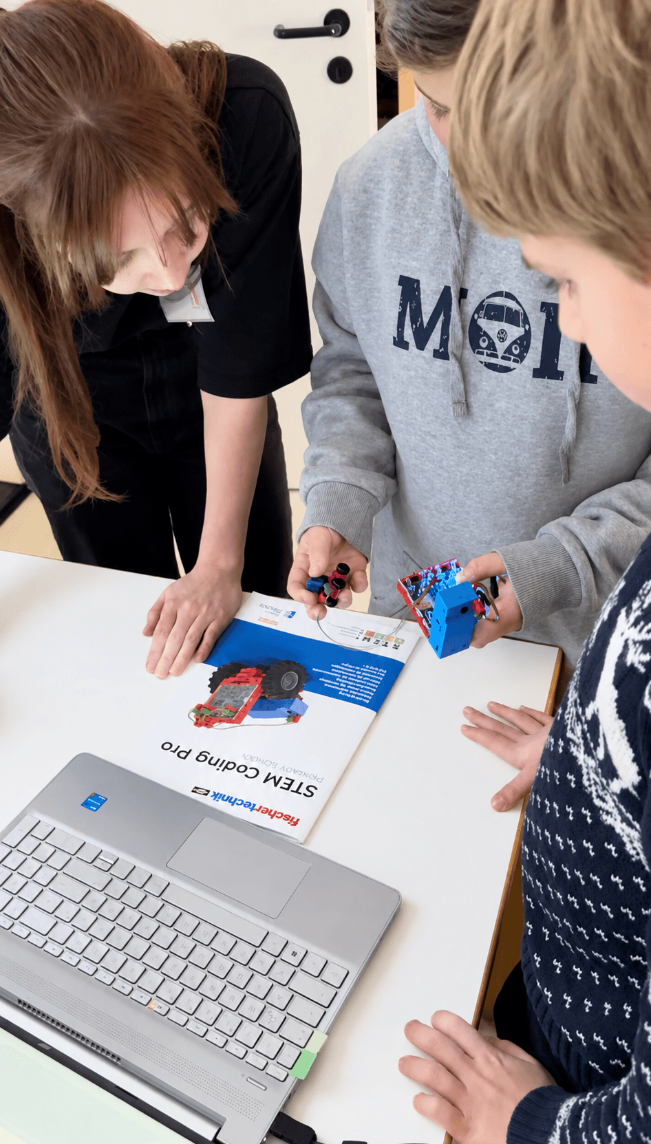 Kinder untersuchen gemeinsam ein technisches Modell am Workshoptisch